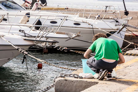 A young man fishing on the pier in Muggia, Trieste, Italyのeditorial素材