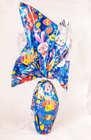 hocolate Easter egg wrapped with blue glossy paper with colorful decorations.の写真素材