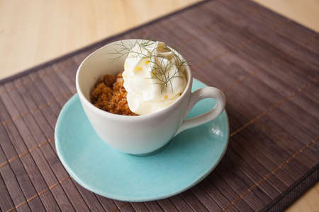 Coffee granite with white chocolate foam and wild fennel, in a blue cup with disch, ambient light.の写真素材