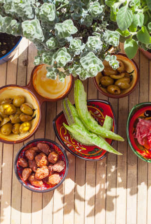 TopView of grapefruit and candied hibiscus flowers, spicy olives, caramelized almonds and aromatic plants in ambient light and shadows. Andalusian Products.の写真素材