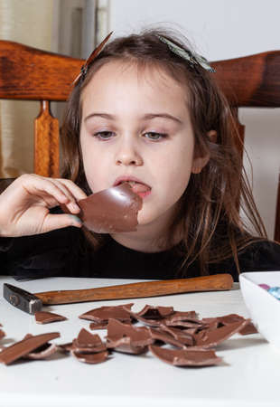 Little girl plays with Easter chocolate egg at homeの写真素材