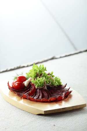 sliced bacon with salad and tomatoes on wooden plateの写真素材