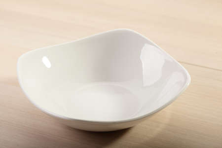 deep white soup plate on bright wooden backgroundの写真素材