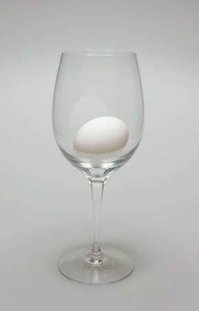 A single egg lying in a wineglass.の写真素材