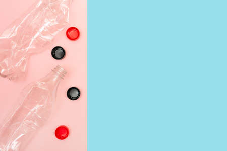 Used and crumpled plastic bottles on pink and blue background with a place for text. Recycling concept. Plastic lids. Rumpled. Reasonable consumption. Flat lay. Copy space.の写真素材