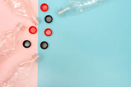 Lots of used and crumpled plastic bottles on pink and blue background with a place for text....