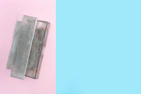 Container from the robot vacuum cleaner with dirt and dust. Flat lay. Pink and blue background. Dust allergy. Place for your text. Copy space. House cleaning.の写真素材
