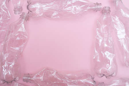 Used and crumpled plastic bottles on pink background with a place for text. Recycling concept. Rumpled. Flat lay. Copy space. Frame made of plastic bottles.の写真素材