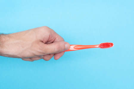 Man holds a toothbrush on a blue background. Copy space. Place for your text. Hygiene of teeth and oral cavity. Dental care. Isolated. Close-up.の写真素材