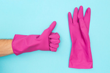 Man in a protective rubber glove. Symbol like. Rubber gloves for cleaning on a blue background. Flat lay.の写真素材