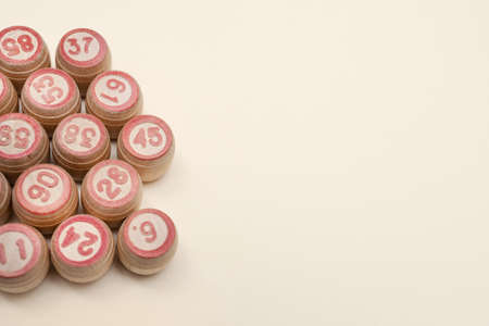 Wooden barrels with numbers for playing lotto or bingo. Beige background. Place for your text. Copy space. Advertising. Flat lay. Leisure with family.の写真素材