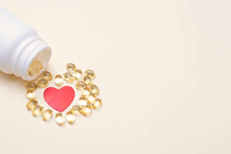 Jar with vitamins D3 and omega 3. Capsules with fish oil. Health care and medicine. Copy space. Place for your text. Heart surrounded by vitaminsの写真素材