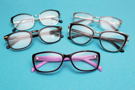 Many different glasses for vision on a blue background. Group of glasses with lenses for vision...