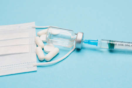 Syringe, pills, vaccine, and medical mask on a blue background. Keep your health. vaccination....