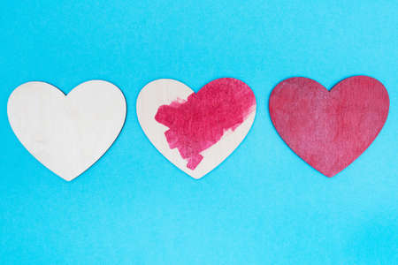Three handmade wooden hearts. painting process. blue background. love concept. flat lay. copyspace....