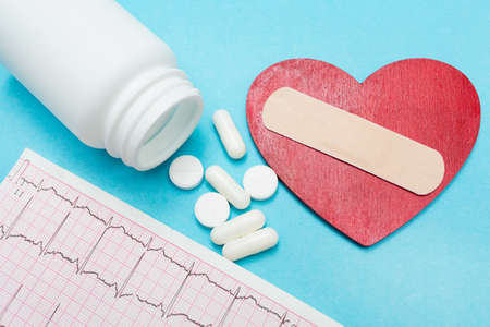 Heart with medical plaster, cardiogram and pills. blue background. Concept of renovation or...