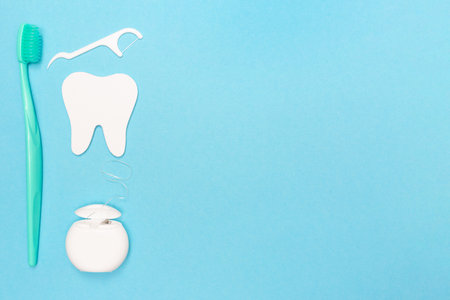 Toothbrush, floss, and tooth model on blue background. Place for text. copyspace. flat lay. top view. dental care kit. oral hygiene.の写真素材
