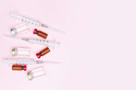 Syringe and vaccine against flu, coronavirus and other diseases on a pink background. Keep your health. Medical treatment concept. Top view. Flat lay. Immunity. Copy space. Place for text.の写真素材