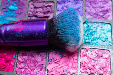 Makeup brush close-up on the background of broken eye shadows. Cosmetic brush. flat lay. top view. beauty concept.の写真素材