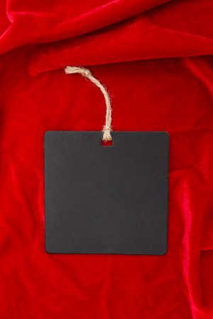 Blank square label on red velvet. black tag. copyspace. Place for text and company . mockup. Top view, flat lay. Price tag label with empty space. vertical.の写真素材