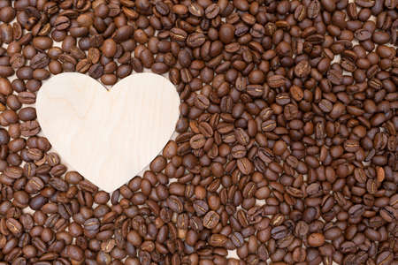 Roasted coffee beans and an empty wooden heart. Place for your text and label. Coffee shop and...