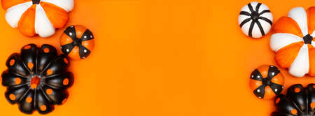 Halloween banner with pumpkins in different colors and sizes. Place for text. Copy space. Flay lay. Top view. Layout for design. Orange background. Halloween card.の写真素材