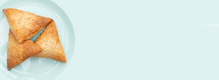 Banner with samsa sprinkled with sesame seeds. Delicious pastries with meat. Place for text. Copy space. Flat lay. Top view. Turquoise Background.の写真素材