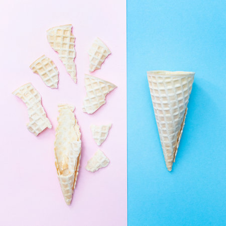 Whole and broken waffle cone for ice cream on a pink and blue background. Top view. Flat layの写真素材