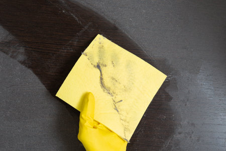 Man in rubber gloves hold a dusty napkin after cleaning against the background of dust. top view