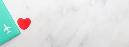 Passport cover with an airplane and a red heart on a marble background. Vacation and rest time. Banner with place for text. Copy space. Top view. Flat layの写真素材