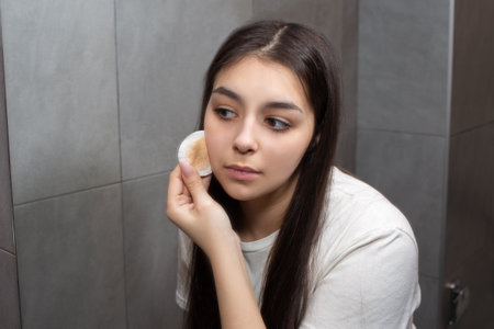 Beautiful young girl removes makeup with a cotton pad.の写真素材
