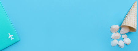 Vacation and rest time. Banner with a passport with an airplane and an ice cream cone with seashells. Copy space. Place for text. Blue background. Top view. Flat lay.の写真素材