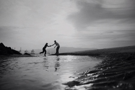 loving couple holding hand crossing the puddle.