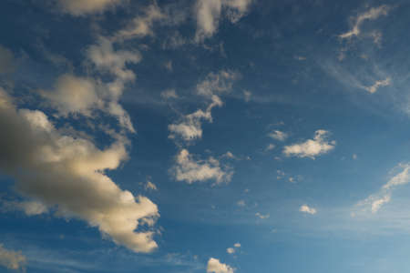 Blue deep sky with a few clouds illuminated by the setting sun.の写真素材
