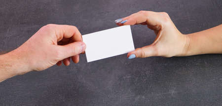 A man and a woman exchange business cards. Close-up view of the hands. Gray stone background.の写真素材