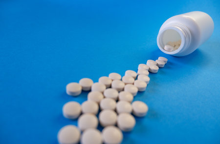 Medicine and healthcare concept. Capsules, tablets scattered near containers on a blue background. Place for your text.の写真素材