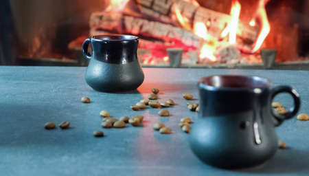 Ceramic coffee cups close-up on the background of burning fire and coffee beans.の写真素材