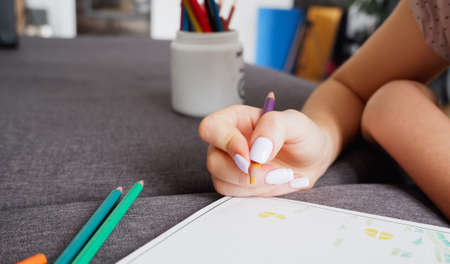 The girl makes a coloring with multi-colored pencils, close-up on hand. Home art hobby.の写真素材