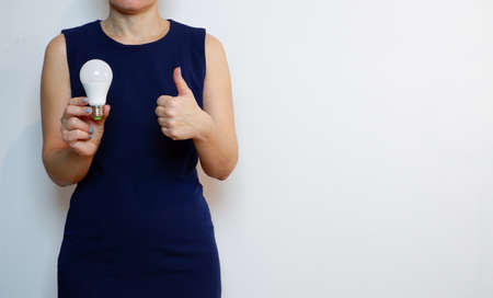 A woman holds a light bulb in her hand. Idea, innovation and inspiration concept, background for copy.の写真素材