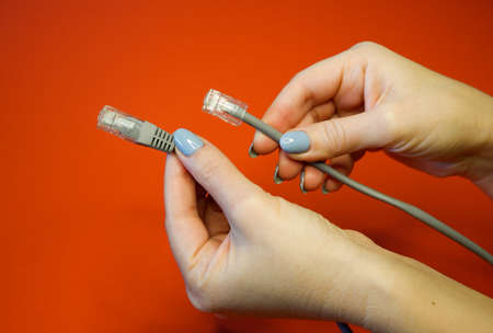 RJ45 network connector on a red background in well-groomed female hands