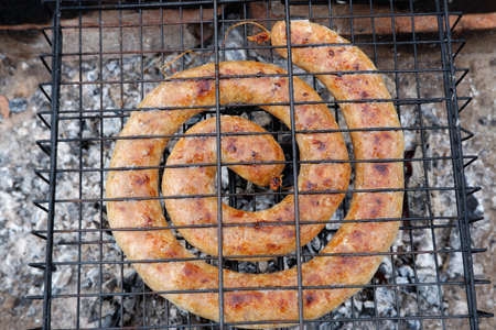 Spiral of homemade sausage is grilled on a charcoal grillの写真素材