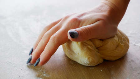 Making homemade dough by female hands on wooden table background. Cooking concept. Female hands with...