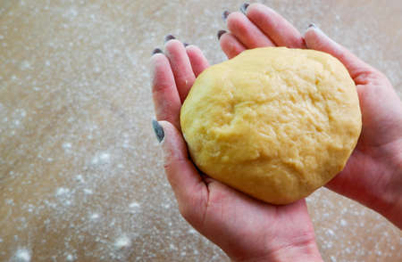 Making homemade dough by female hands on wooden table background. Cooking concept. Female hands with dough.の写真素材