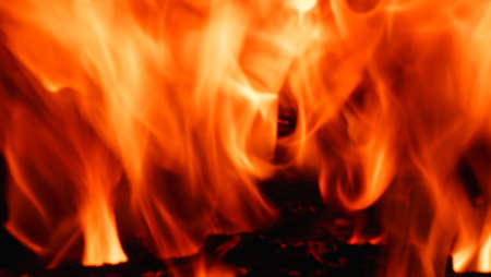 Abstract fire flame in the fireplace, texture for background. Beautiful, bright orange flames flicker in the darkness of the night.の写真素材