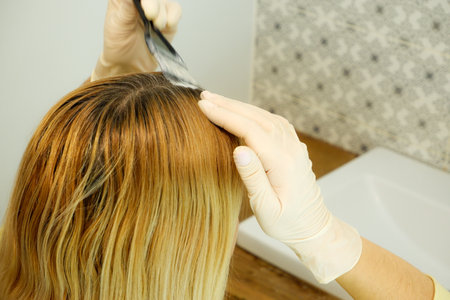 Hair coloring at home. The girl herself dyes the regrown hair roots.の写真素材