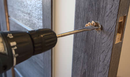 Insert of latch and handle into the interior door. Close-up view of the work process.の写真素材