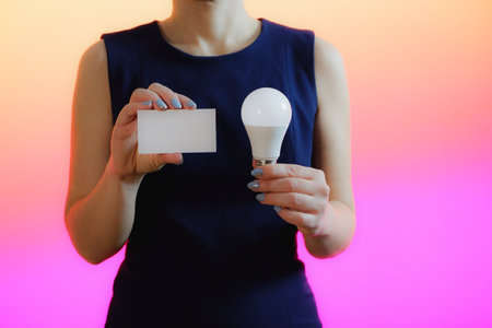 A woman holds a light bulb in her hand. Idea, innovation and inspiration concept, background for copy.の写真素材