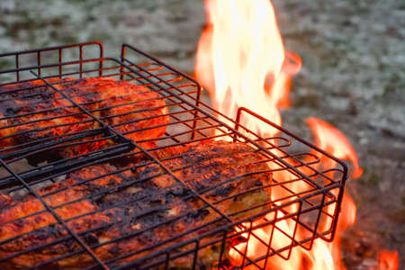 Cooking chicken meat over charcoal. Chicken meat fried with a crust on a wire rack during grill...