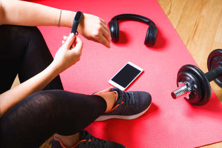 Home workout. An unrecognizable woman is proud for a run after a dumbbell workout. Headphones...