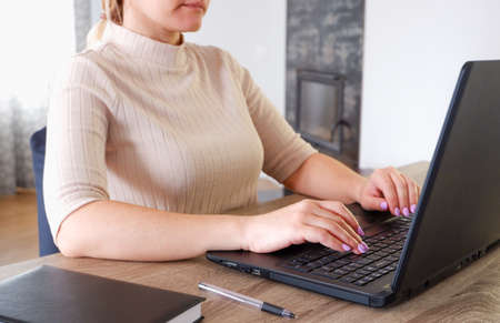 A young attractive woman, sitting at a table with a lapto, fills out tax reports. Calculation of...